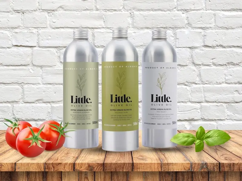 albanian brand little olive oil, three products from Little Olive Oil in aluminium bottles against a white brick wall